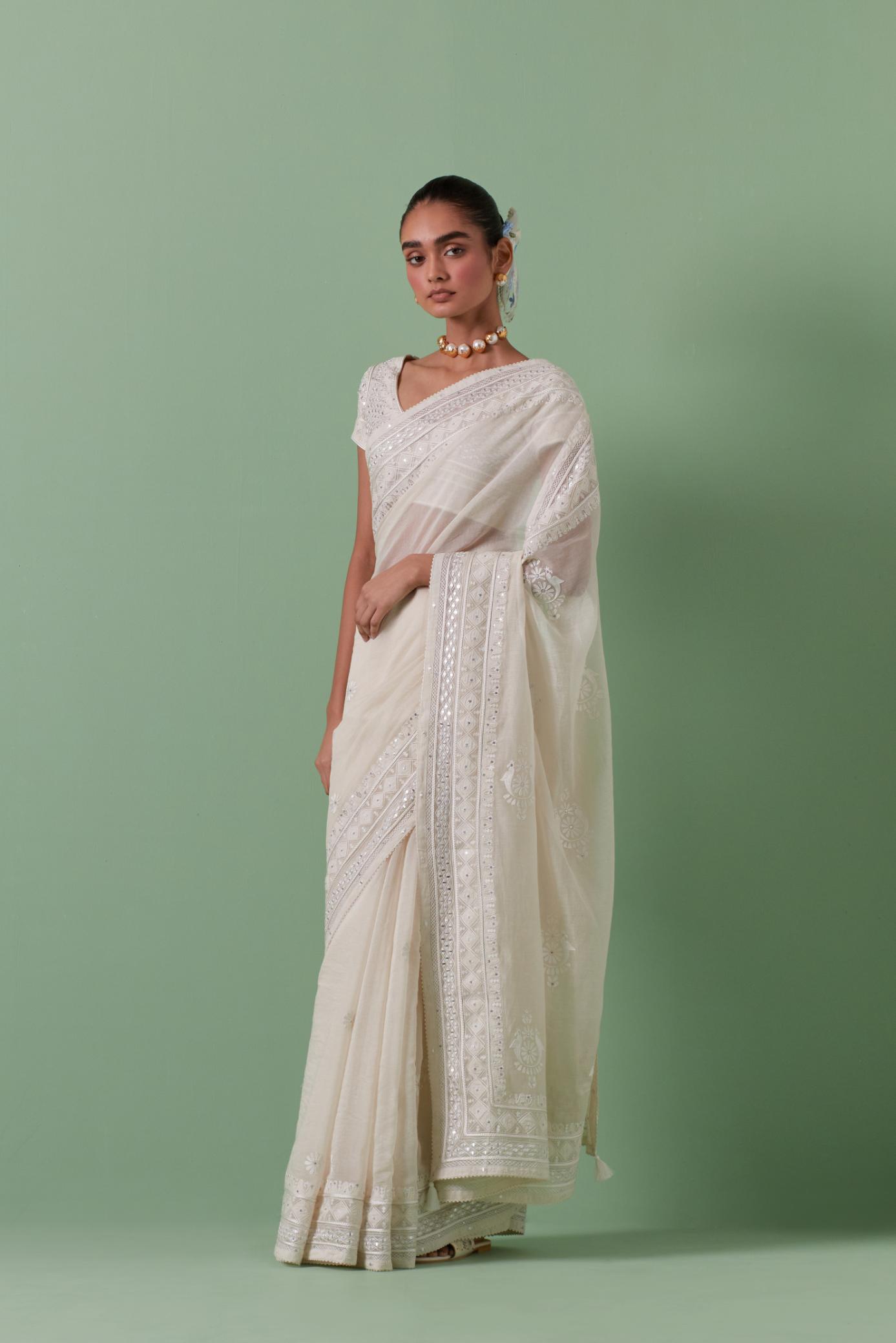 Off-white cotton chanderi saree with delicate silk thread embroidery, highlighted with braids, mirrors and sequins, paired with off white cotton chanderi embroidered blouse with deep round neck and princess seams.