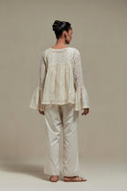 Off white cotton Chanderi short top with appliqué motifs and delicate embroidered flowers, highlighted with sequins and beads, paired with Off white straight pants with appliqué motifs at the sides, highlighted with sequins and beads.