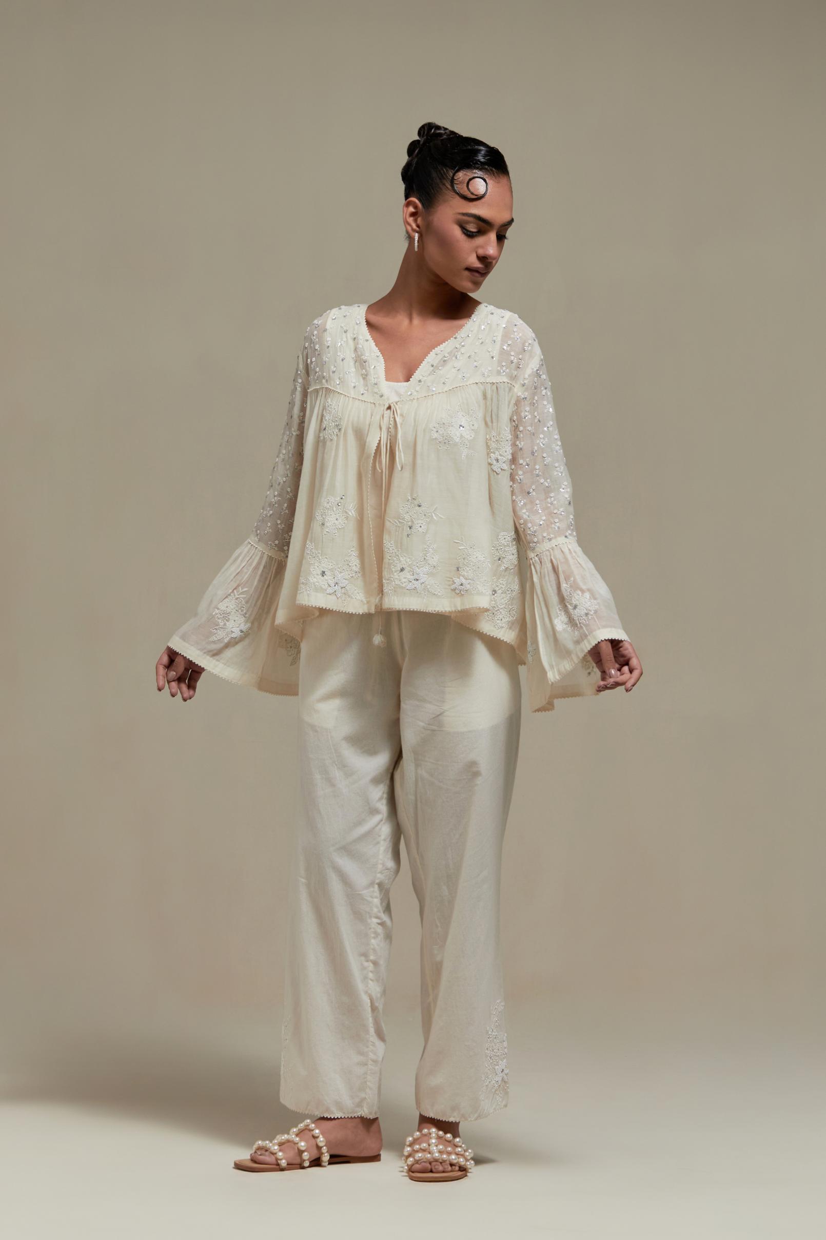Off white cotton Chanderi short top with appliqué motifs and delicate embroidered flowers, highlighted with sequins and beads, paired with Off white straight pants with appliqué motifs at the sides, highlighted with sequins and beads.