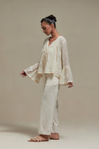 Off white cotton Chanderi short top with appliqué motifs and delicate embroidered flowers, highlighted with sequins and beads, paired with Off white straight pants with appliqué motifs at the sides, highlighted with sequins and beads.