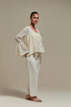 Off white cotton Chanderi short top with appliqué motifs and delicate embroidered flowers, highlighted with sequins and beads, paired with Off white straight pants with appliqué motifs at the sides, highlighted with sequins and beads.