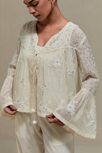 Off white cotton Chanderi short top with appliqué motifs and delicate embroidered flowers, highlighted with sequins and beads, paired with Off white straight pants with appliqué motifs at the sides, highlighted with sequins and beads.