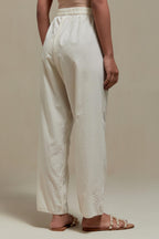 Off white straight pants with appliqué motifs at the sides, highlighted with sequins and beads.