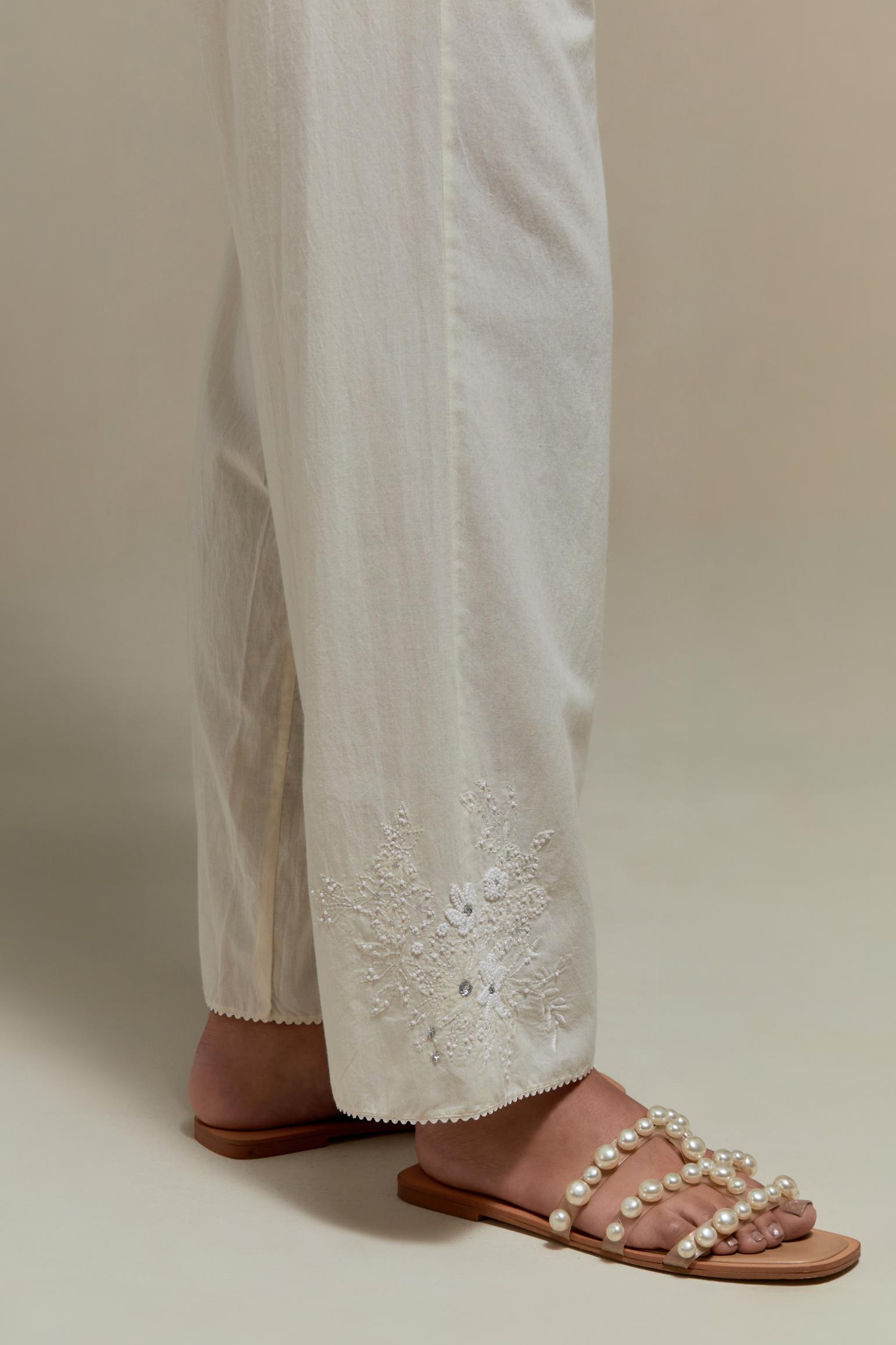 Off white straight pants with appliqué motifs at the sides, highlighted with sequins and beads.