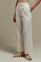 Off white straight pants with appliqué motifs at the sides, highlighted with sequins and beads.