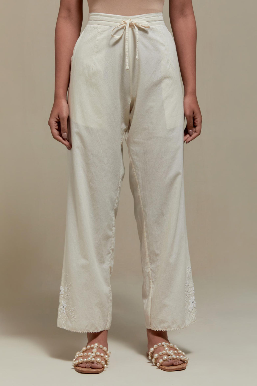 Off white straight pants with appliqué motifs at the sides, highlighted with sequins and beads.