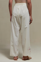 Off white straight pants with pink & beige hand block printed appliqué motifs at the sides, highlighted with sequins and multi coloured beads.