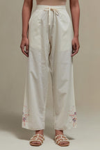 Off white straight pants with pink & beige hand block printed appliqué motifs at the sides, highlighted with sequins and multi coloured beads.