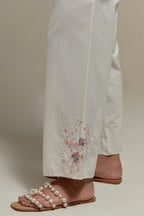 Off white straight pants with pink & beige hand block printed appliqué motifs at the sides, highlighted with sequins and multi coloured beads.