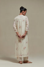 Off white cotton Chanderi straight kurta set with randomly placed pink & beige hand block printed appliquéd flowers, highlighted with sequins and multi coloured beads.