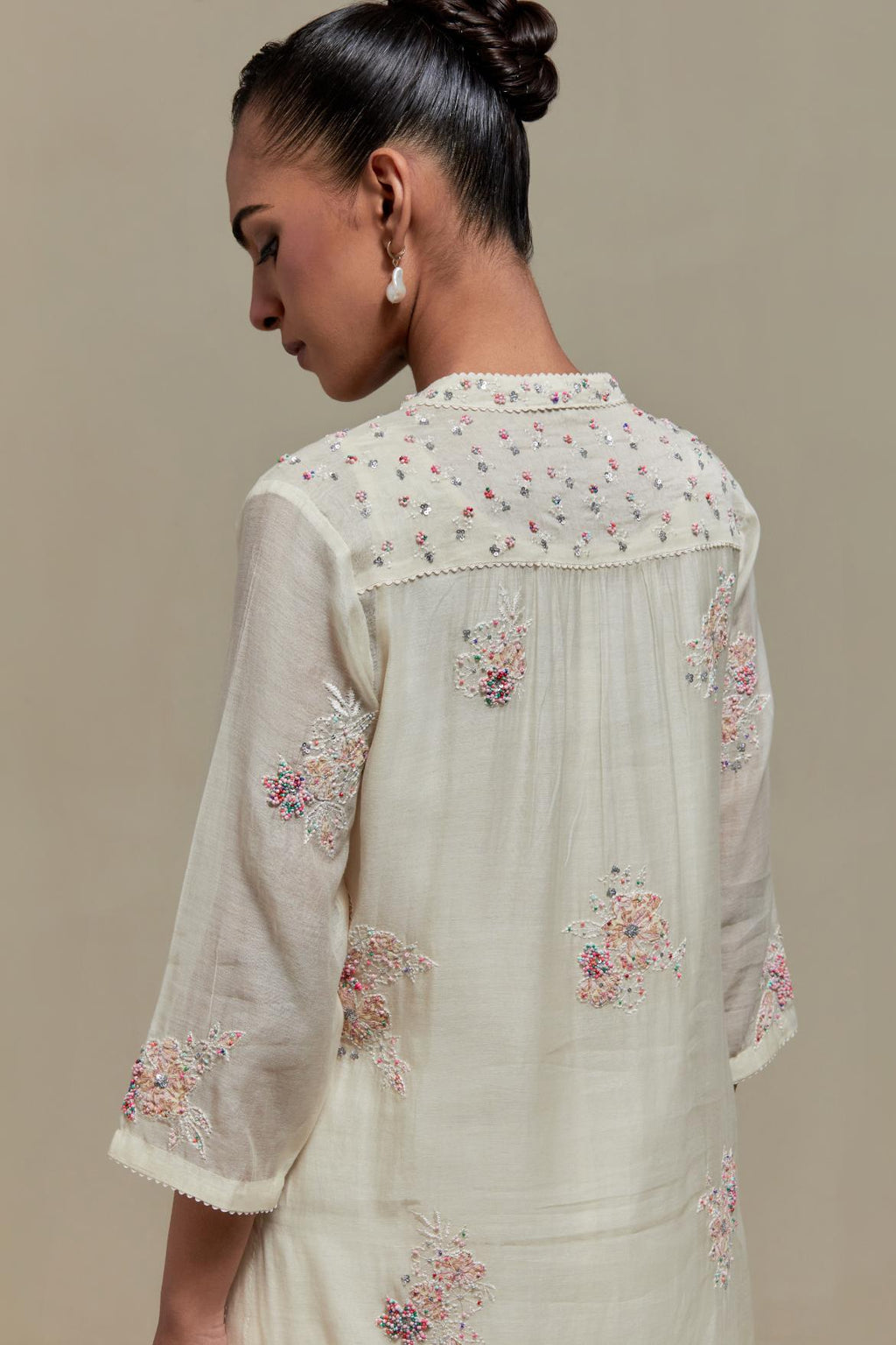 Off white cotton Chanderi straight kurta set with randomly placed pink & beige hand block printed appliquéd flowers, highlighted with sequins and multi coloured beads.