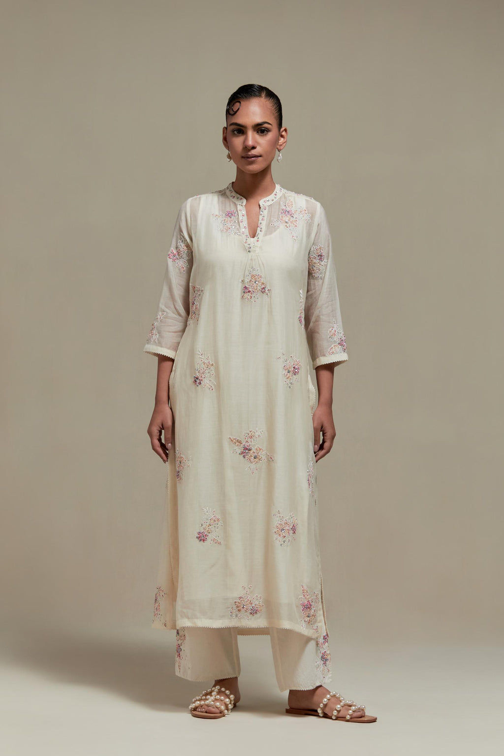 Off white cotton Chanderi straight kurta set with randomly placed pink & beige hand block printed appliquéd flowers, highlighted with sequins and multi coloured beads.