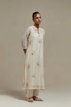 Off white cotton Chanderi straight kurta set with randomly placed pink & beige hand block printed appliquéd flowers, highlighted with sequins and multi coloured beads.