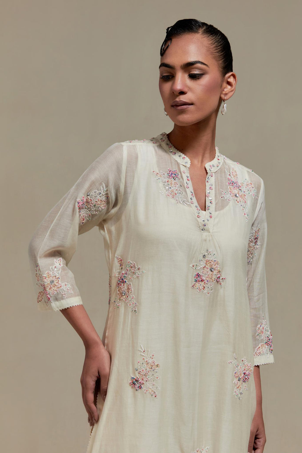 Off white cotton Chanderi straight kurta set with randomly placed pink & beige hand block printed appliquéd flowers, highlighted with sequins and multi coloured beads.