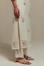 Off white cotton Chanderi straight kurta set with randomly placed pink & beige hand block printed appliquéd flowers, highlighted with sequins and multi coloured beads.