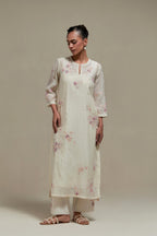 Off white cotton Chanderi straight kurta set with randomly placed pink & beige hand block printed appliquéd flowers, highlighted with sequins and multi coloured beads.
