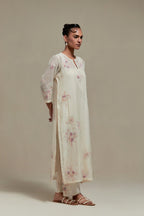 Off white cotton Chanderi straight kurta set with randomly placed pink & beige hand block printed appliquéd flowers, highlighted with sequins and multi coloured beads.