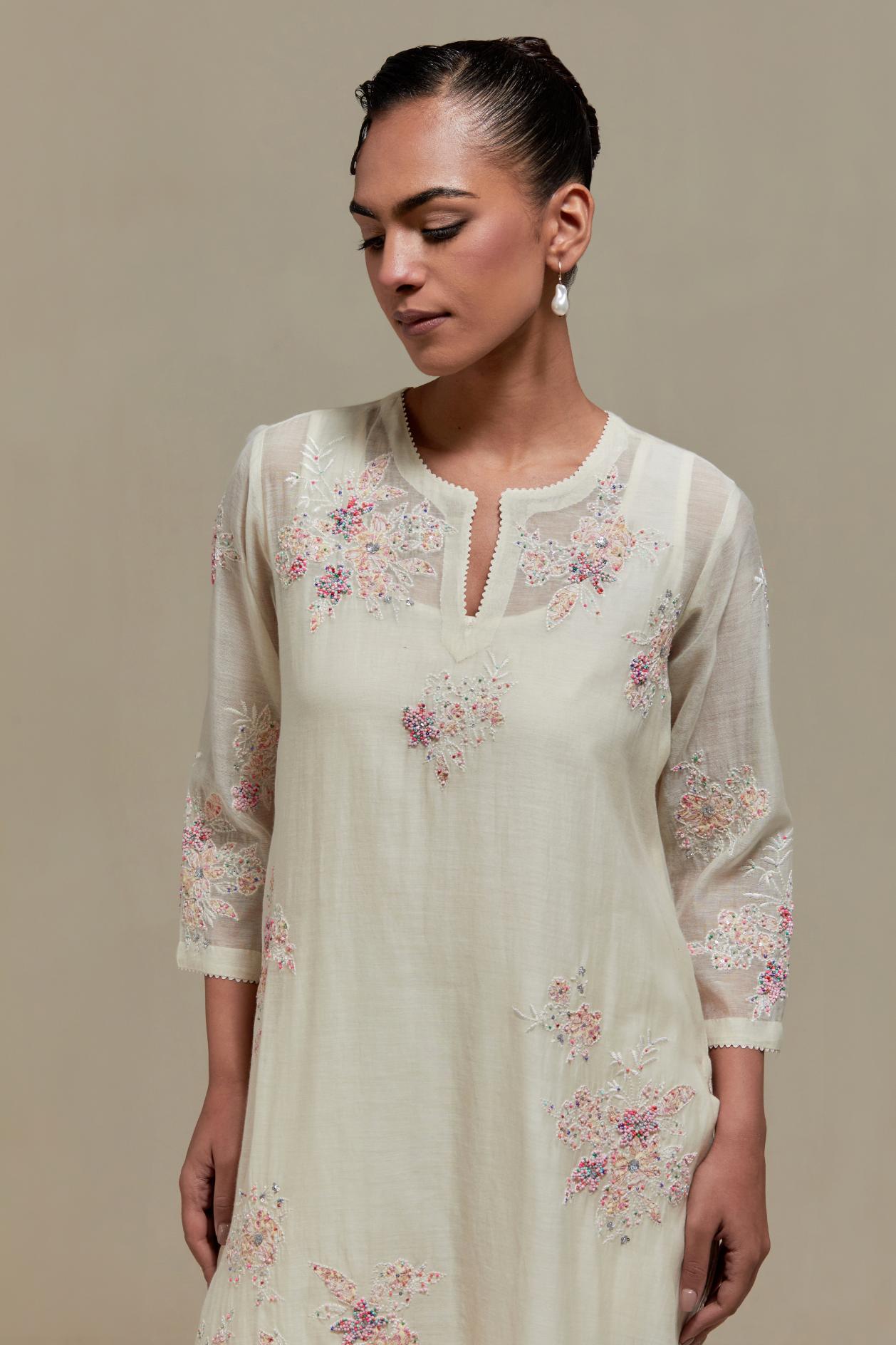 Off white cotton Chanderi straight kurta set with randomly placed pink & beige hand block printed appliquéd flowers, highlighted with sequins and multi coloured beads.