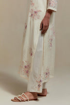 Off white cotton Chanderi straight kurta set with randomly placed pink & beige hand block printed appliquéd flowers, highlighted with sequins and multi coloured beads.
