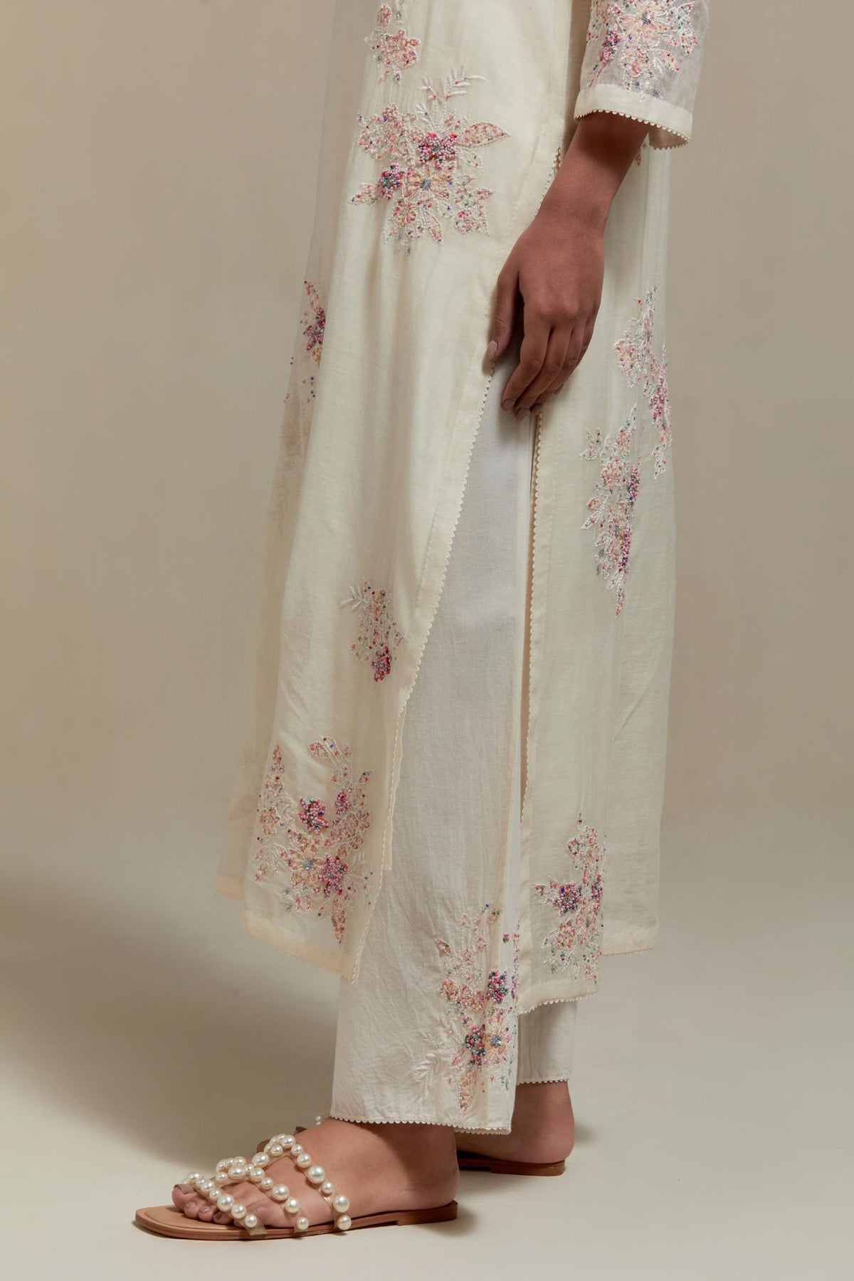 Off white cotton Chanderi straight kurta set with randomly placed pink & beige hand block printed appliquéd flowers, highlighted with sequins and multi coloured beads.
