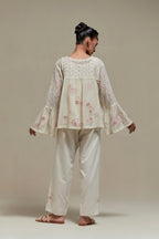 Off-white cotton Chanderi short top featuring pink & beige block print appliqué, floral embroidery, and beadwork. Paired with matching straight pants with side appliqué and sequin highlights. Ideal for elegant, light wear.