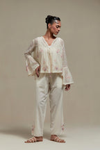 Off-white cotton Chanderi short top featuring pink & beige block print appliqué, floral embroidery, and beadwork. Paired with matching straight pants with side appliqué and sequin highlights. Ideal for elegant, light wear.
