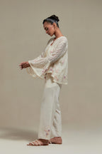Off-white cotton Chanderi short top featuring pink & beige block print appliqué, floral embroidery, and beadwork. Paired with matching straight pants with side appliqué and sequin highlights. Ideal for elegant, light wear.