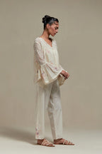 Off-white cotton Chanderi short top featuring pink & beige block print appliqué, floral embroidery, and beadwork. Paired with matching straight pants with side appliqué and sequin highlights. Ideal for elegant, light wear.