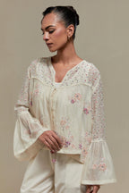 Off-white cotton Chanderi short top featuring pink & beige block print appliqué, floral embroidery, and beadwork. Paired with matching straight pants with side appliqué and sequin highlights. Ideal for elegant, light wear.