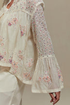 Off-white cotton Chanderi short top featuring pink & beige block print appliqué, floral embroidery, and beadwork. Paired with matching straight pants with side appliqué and sequin highlights. Ideal for elegant, light wear.