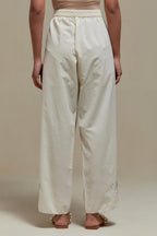 Off white straight pants with blue & beige hand block printed appliqué motifs at the sides, highlighted with sequins and multi coloured beads.