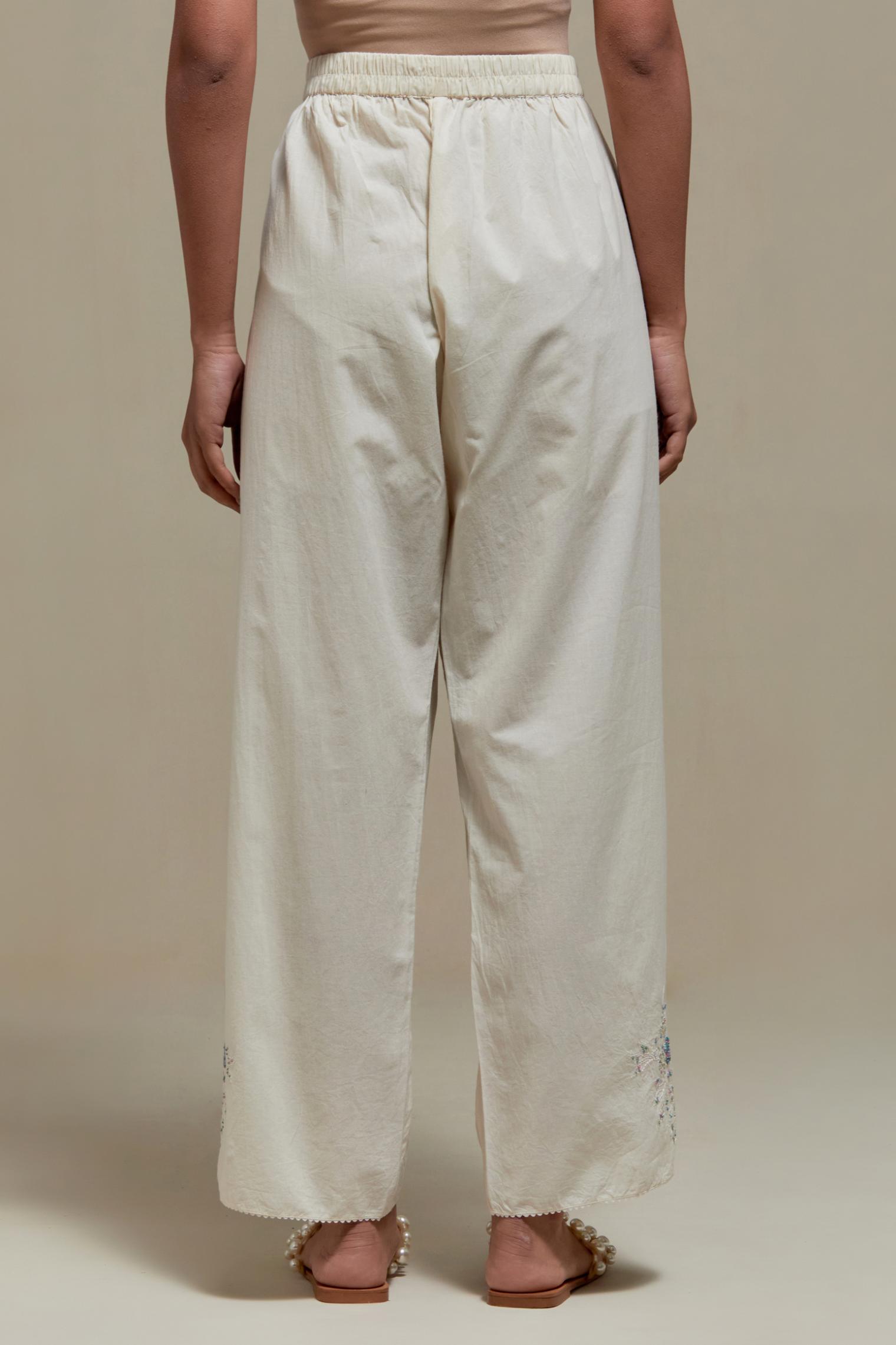 Off white straight pants with blue & beige hand block printed appliqué motifs at the sides, highlighted with sequins and multi coloured beads.
