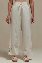 Off white straight pants with blue & beige hand block printed appliqué motifs at the sides, highlighted with sequins and multi coloured beads.