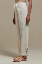Off white straight pants with blue & beige hand block printed appliqué motifs at the sides, highlighted with sequins and multi coloured beads.