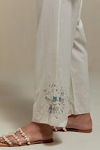 Off white straight pants with blue & beige hand block printed appliqué motifs at the sides, highlighted with sequins and multi coloured beads.