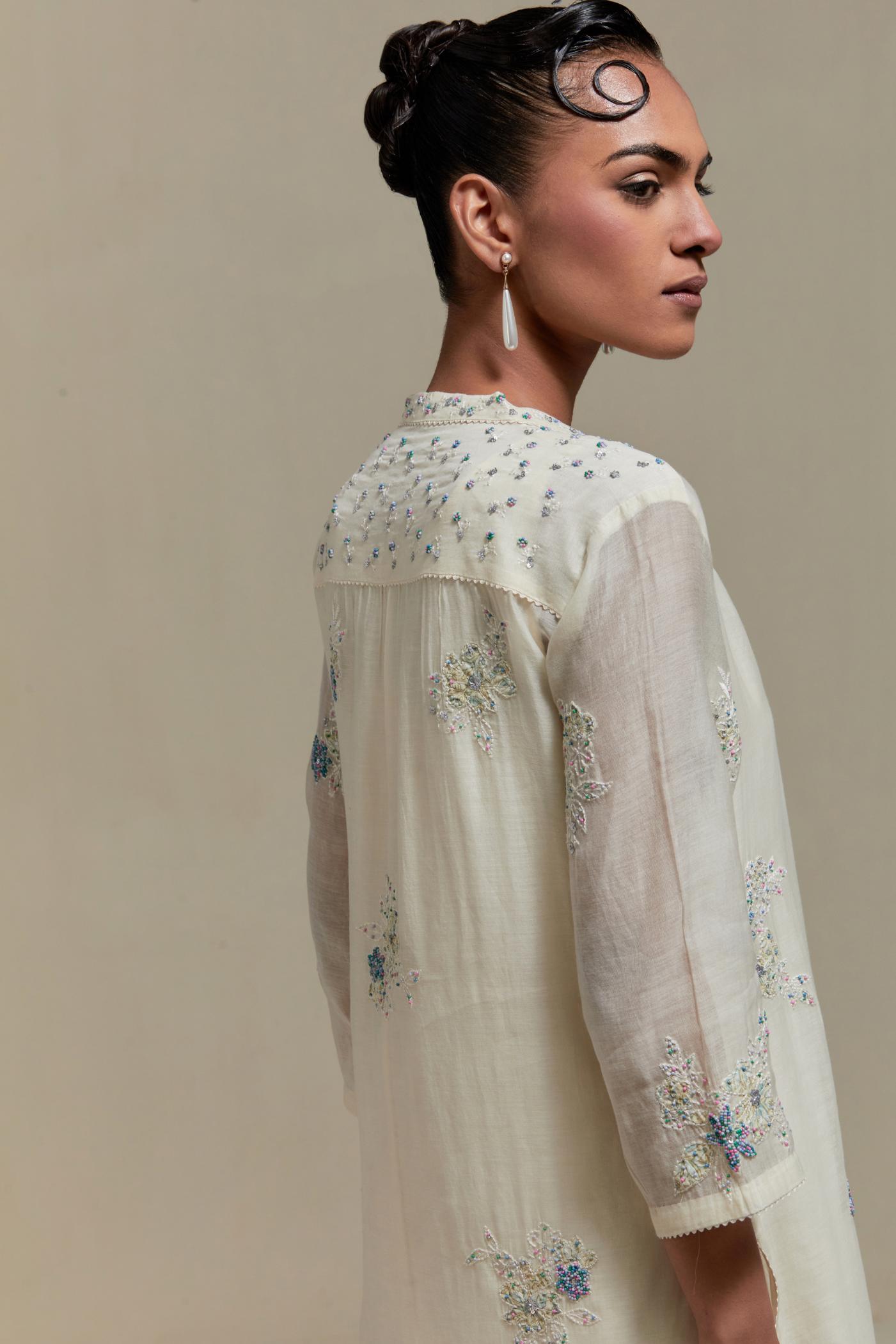 Off white cotton Chanderi straight kurta set with randomly placed blue & beige hand block printed appliquéd flowers, highlighted with sequins and multi coloured beads.