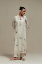 Off white cotton Chanderi straight kurta set with randomly placed blue & beige hand block printed appliquéd flowers, highlighted with sequins and multi coloured beads.