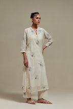Off white cotton Chanderi straight kurta set with randomly placed blue & beige hand block printed appliquéd flowers, highlighted with sequins and multi coloured beads.