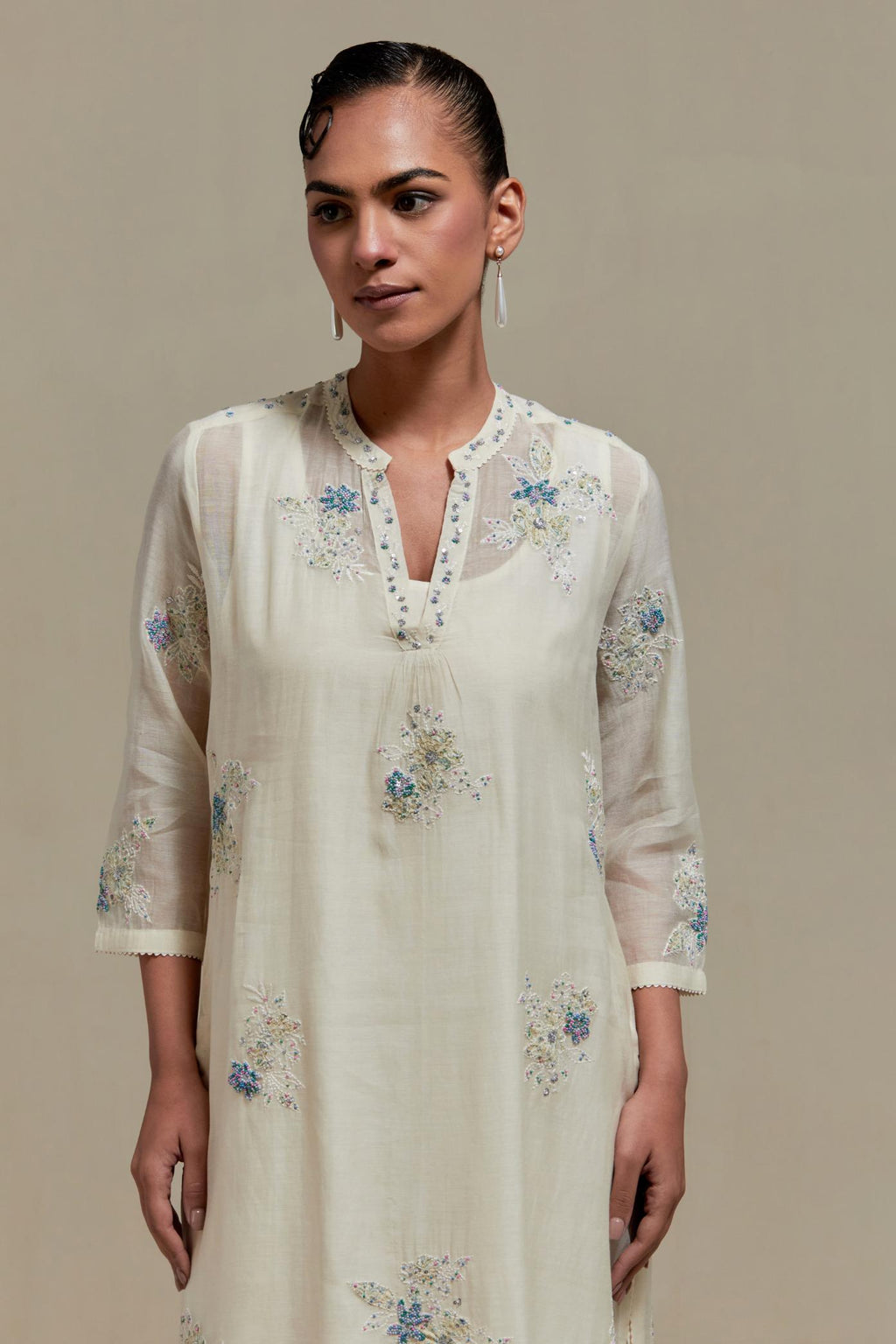 Off white cotton Chanderi straight kurta set with randomly placed blue & beige hand block printed appliquéd flowers, highlighted with sequins and multi coloured beads.