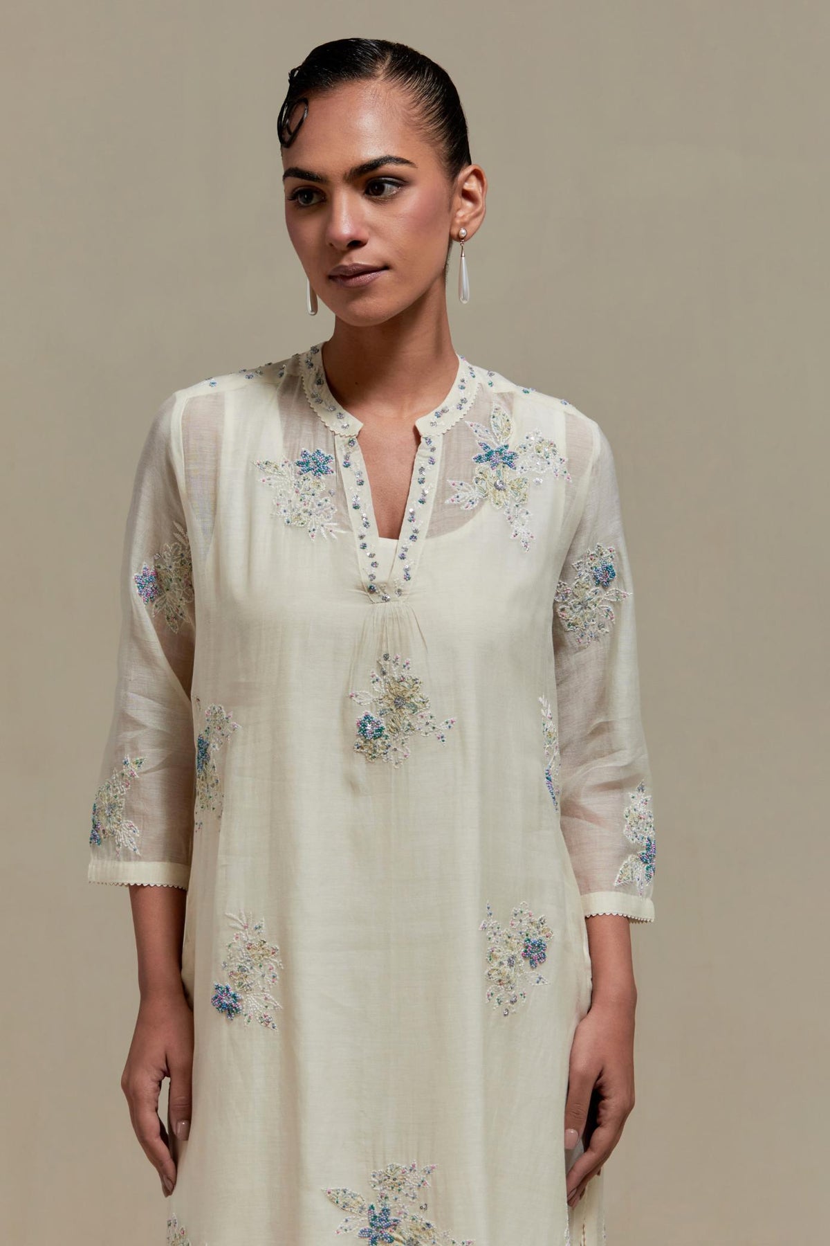 Off white cotton Chanderi straight kurta set with randomly placed blue & beige hand block printed appliquéd flowers, highlighted with sequins and multi coloured beads.