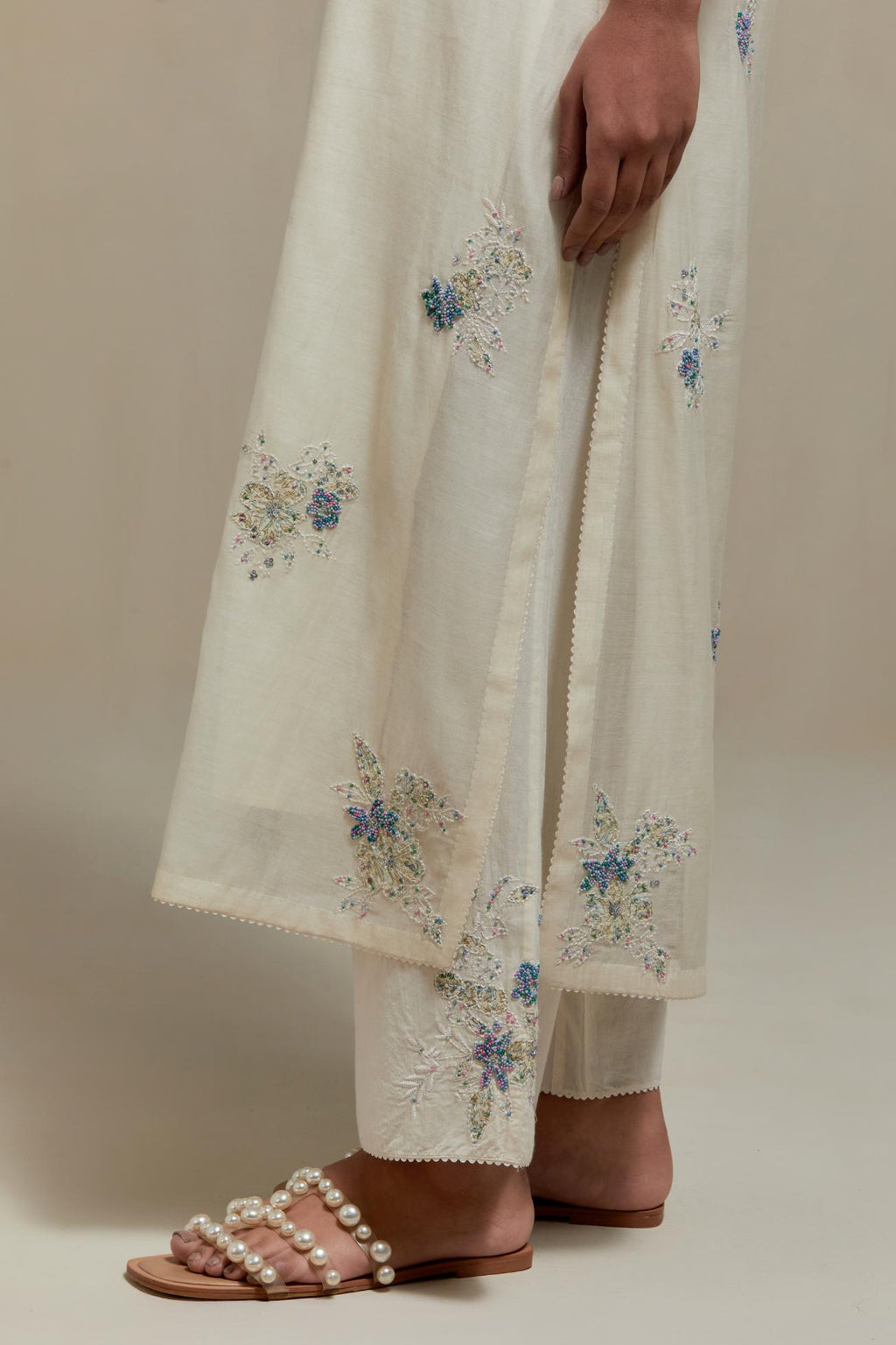 Off white cotton Chanderi straight kurta set with randomly placed blue & beige hand block printed appliquéd flowers, highlighted with sequins and multi coloured beads.