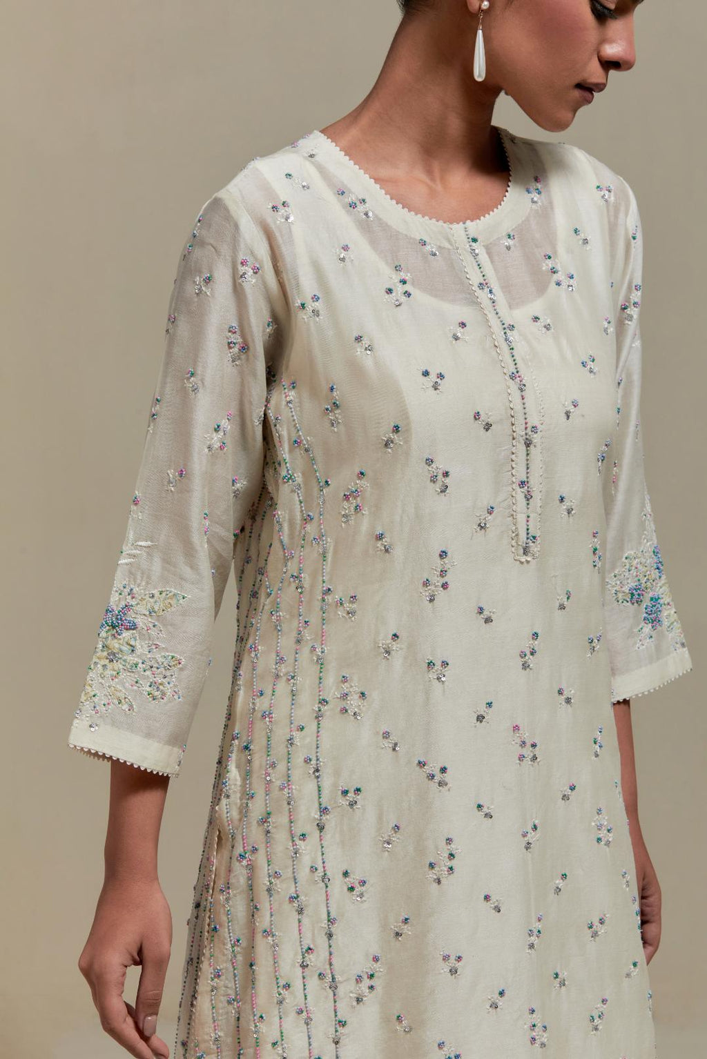Off white silk Chanderi straight kurta set with all-over delicate embroidered flowers, highlighted with sequins and multi coloured beads.