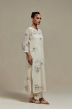 Off white cotton Chanderi straight kurta set with randomly placed blue & beige hand block printed appliquéd flowers, highlighted with sequins and multi colored beads.