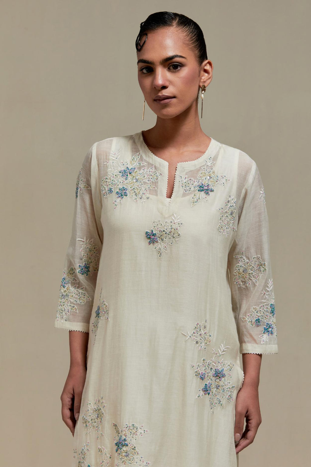 Off white cotton Chanderi straight kurta set with randomly placed blue & beige hand block printed appliquéd flowers, highlighted with sequins and multi colored beads.