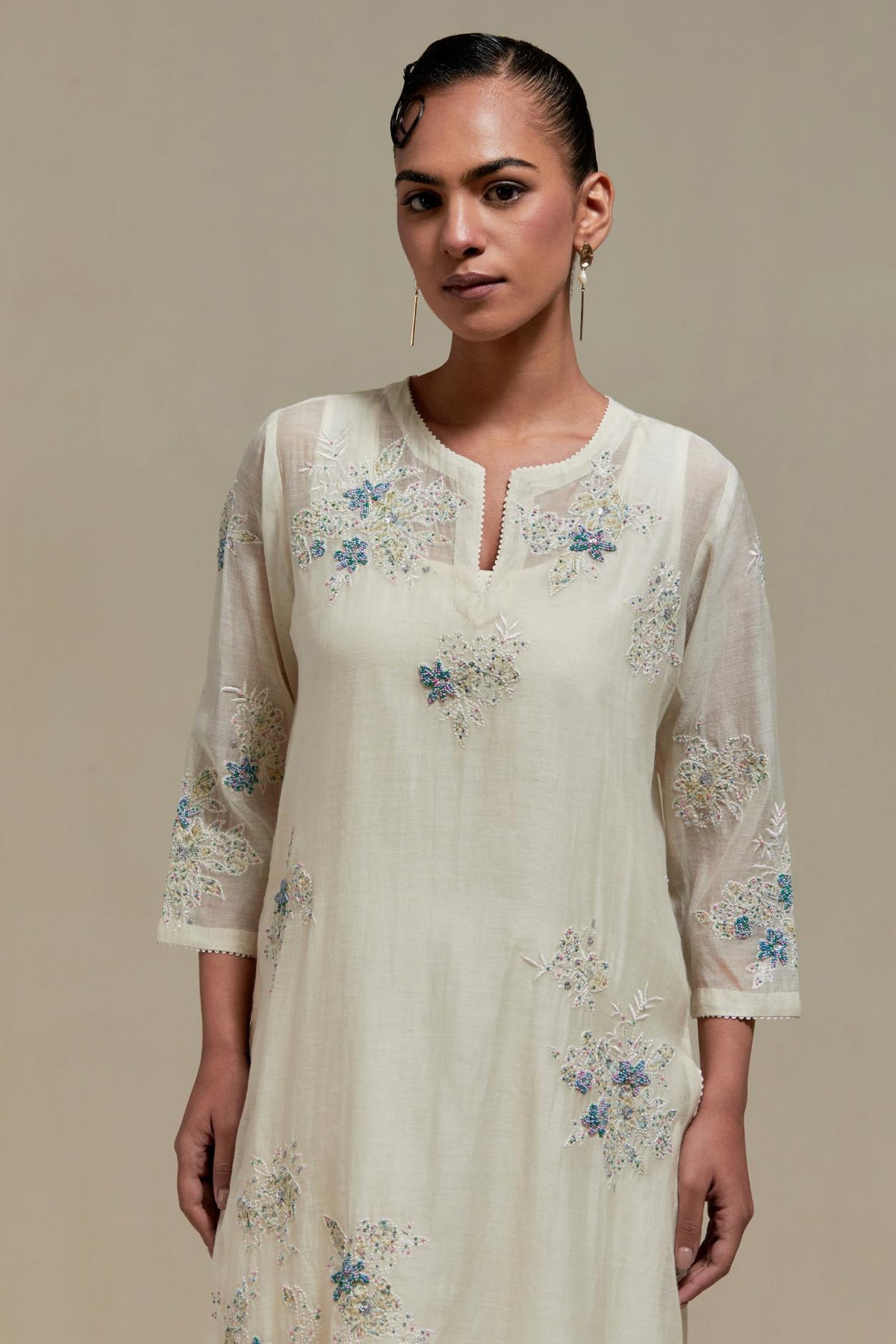 Off white cotton Chanderi straight kurta set with randomly placed blue & beige hand block printed appliquéd flowers, highlighted with sequins and multi colored beads.