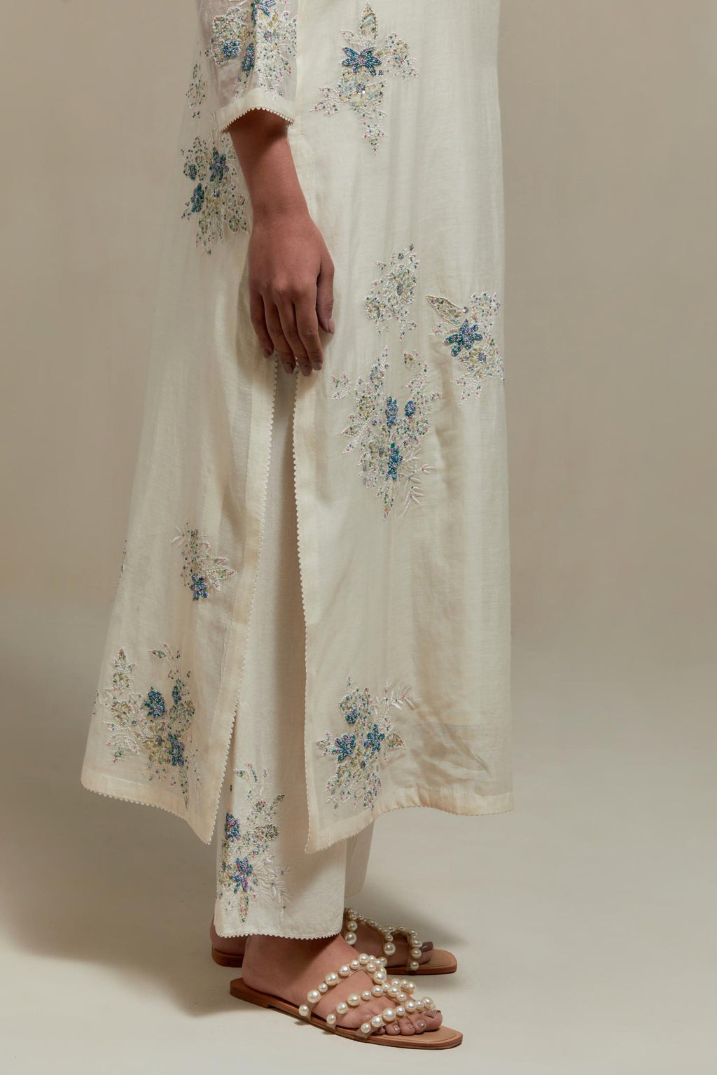 Off white cotton Chanderi straight kurta set with randomly placed blue & beige hand block printed appliquéd flowers, highlighted with sequins and multi colored beads.