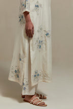 Off white cotton Chanderi straight kurta set with randomly placed blue & beige hand block printed appliquéd flowers, highlighted with sequins and multi colored beads.