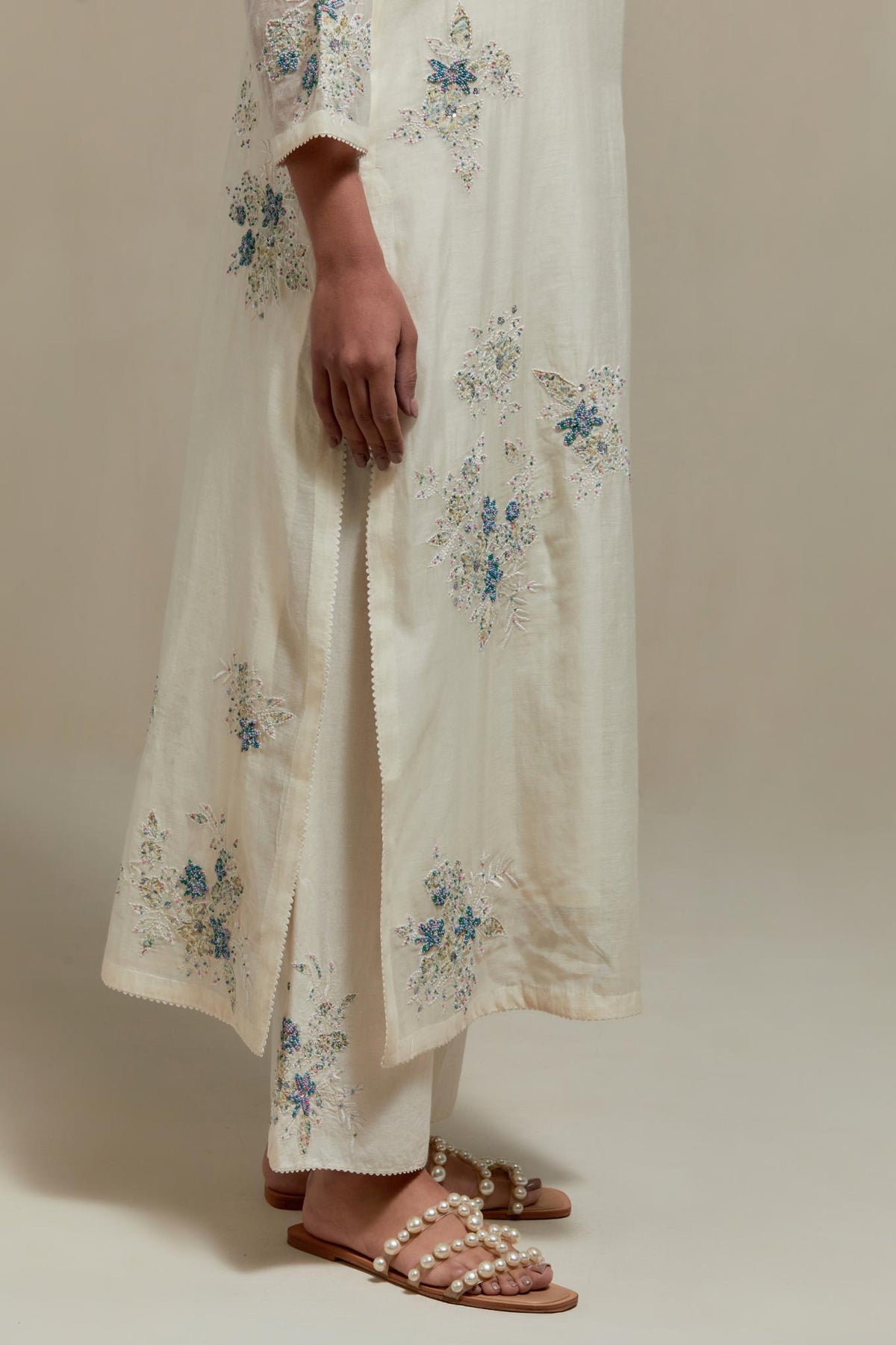 Off white cotton Chanderi straight kurta set with randomly placed blue & beige hand block printed appliquéd flowers, highlighted with sequins and multi colored beads.