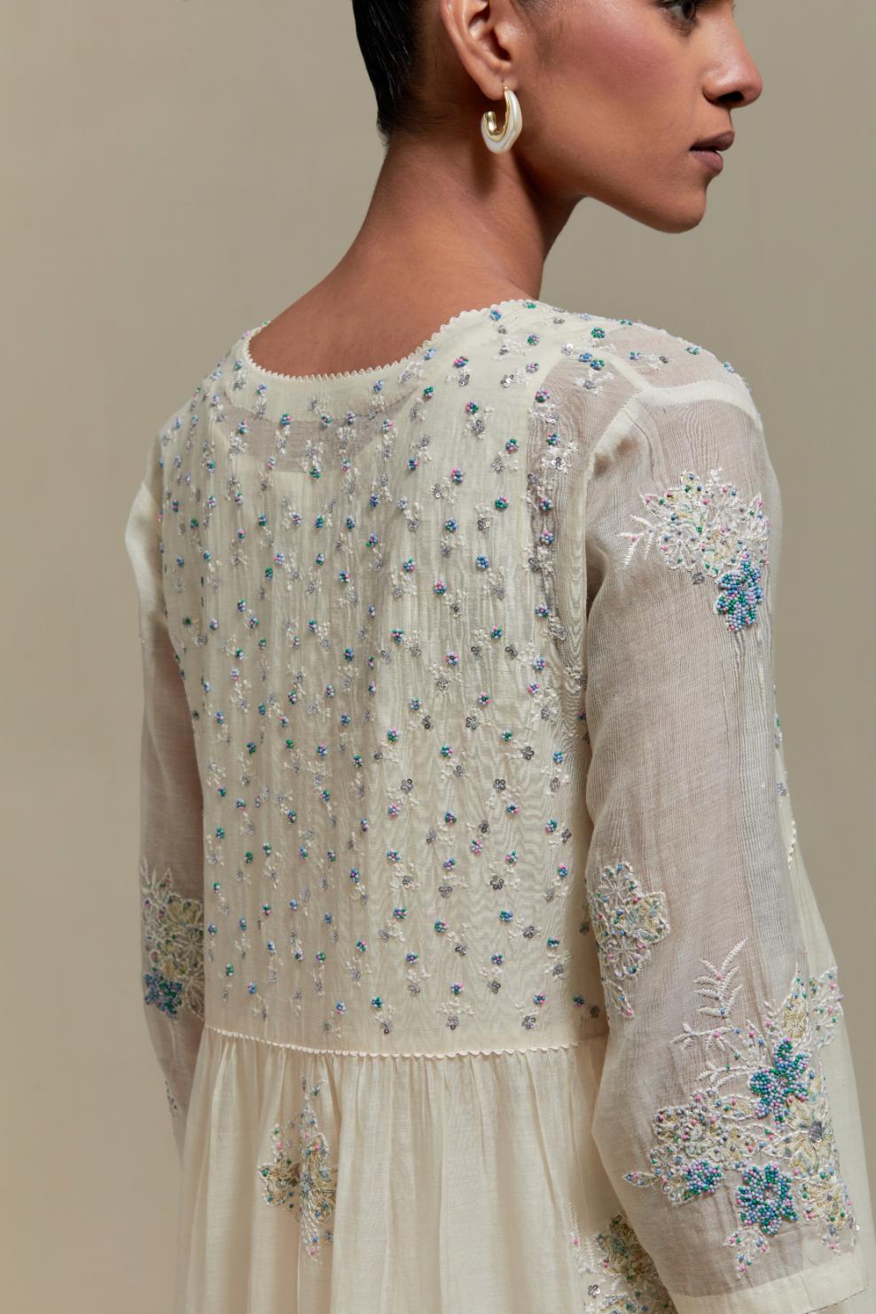 Off white cotton Chanderi kurta dress set with delicate embroidered flowers and blue & beige hand block printed appliqué motifs, highlighted with sequins and multi coloured beads.