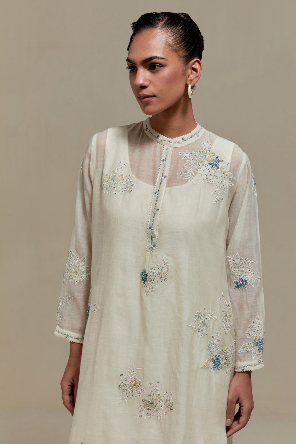Off white cotton Chanderi short kurta set with all-over blue & beige hand block printed appliqué, highlighted with sequins and multi coloured beads.